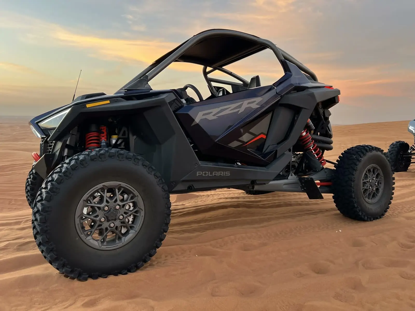 Abu Buggy, black buggy parked on dune at sunset