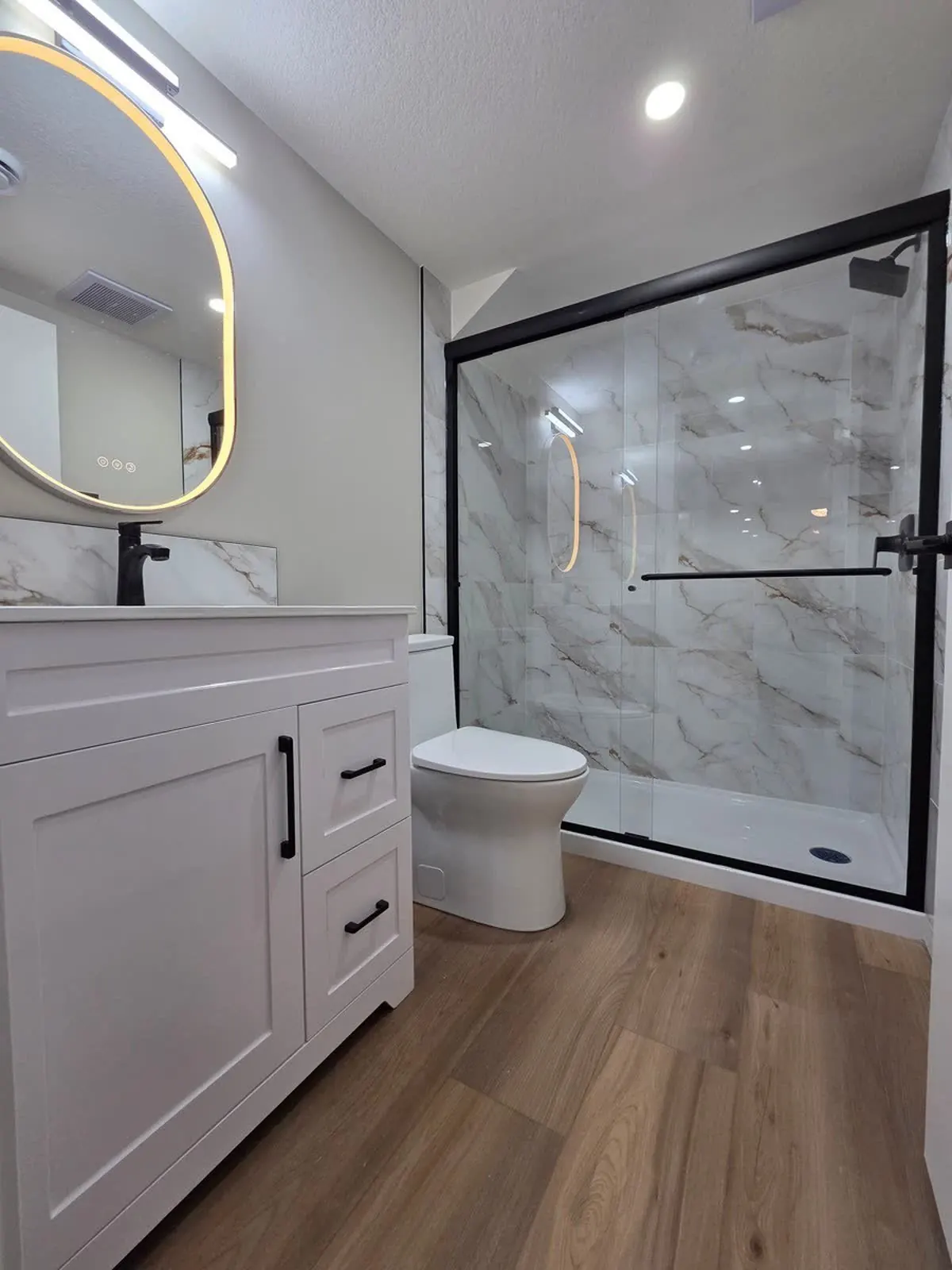 Grains Construction, bathroom with glass shower and round mirror